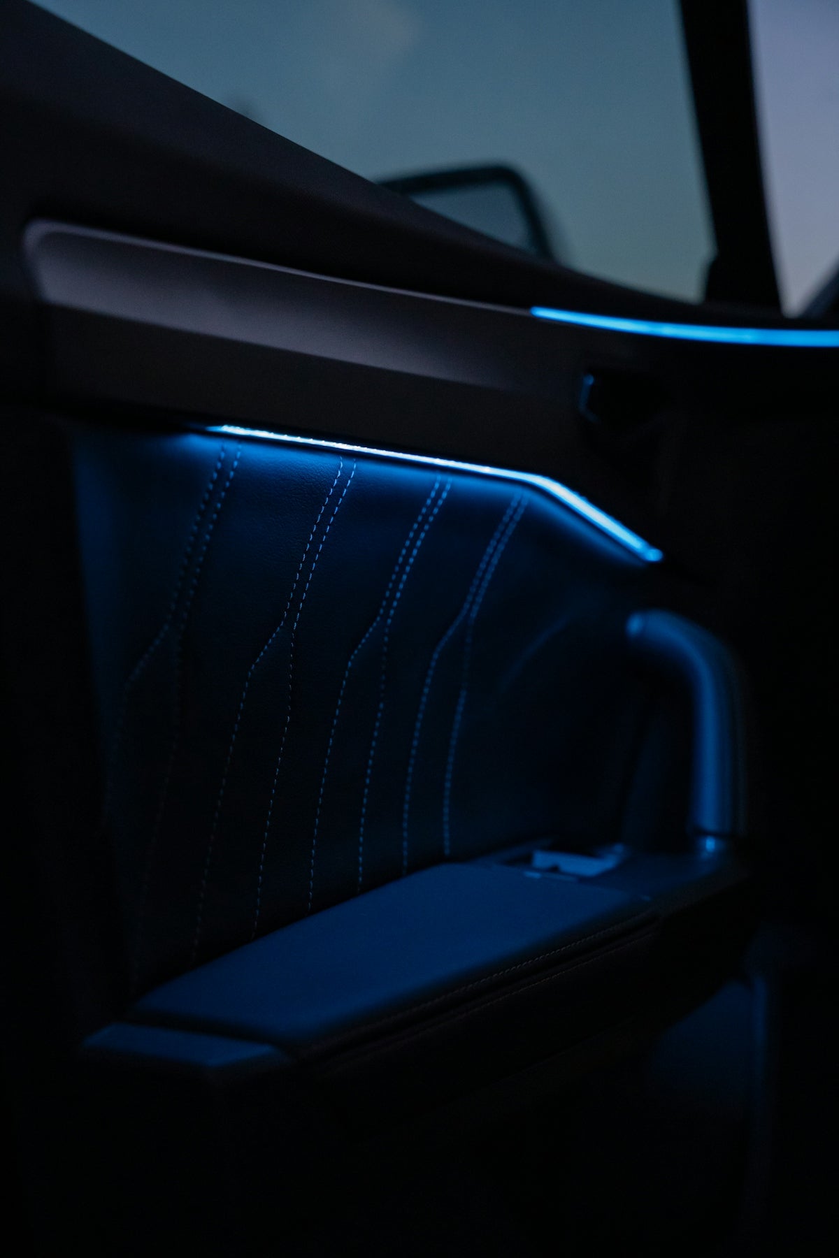 Interior car door panel with blue ambient lighting.